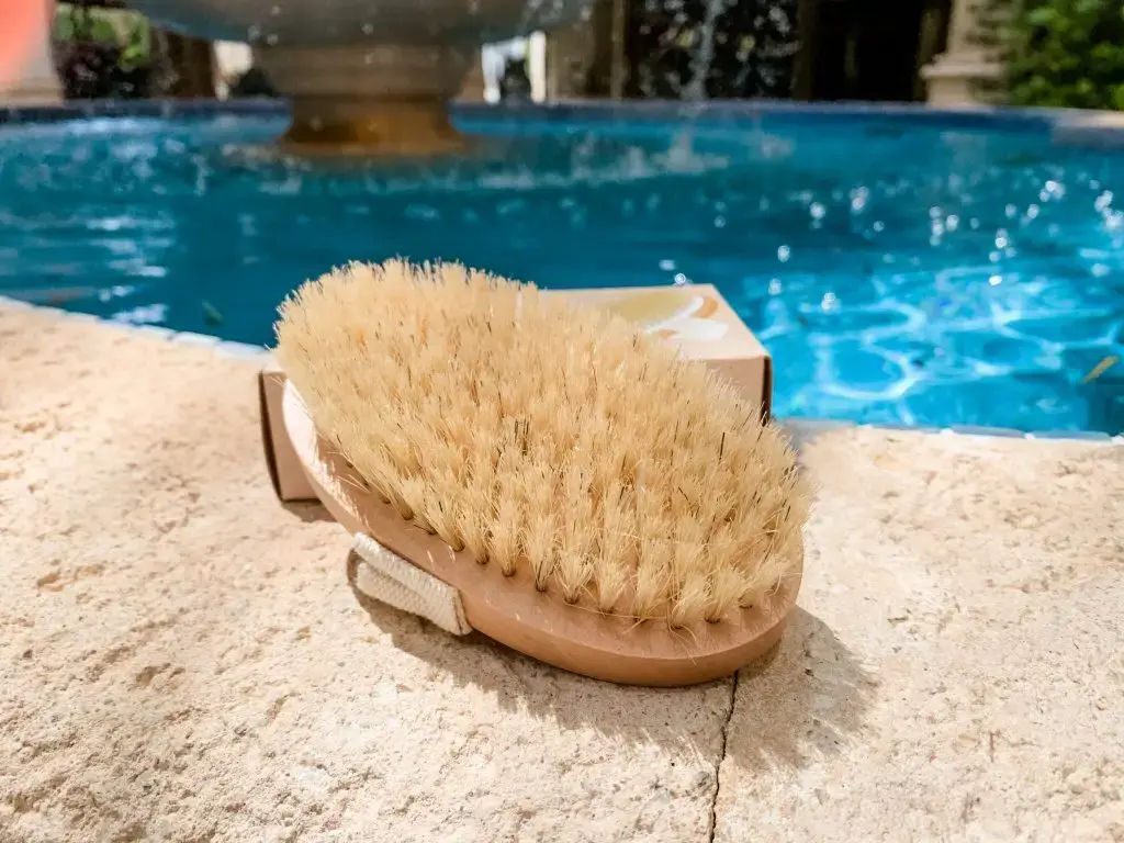Body brush on a tile next to a pool for dry body brushing.
