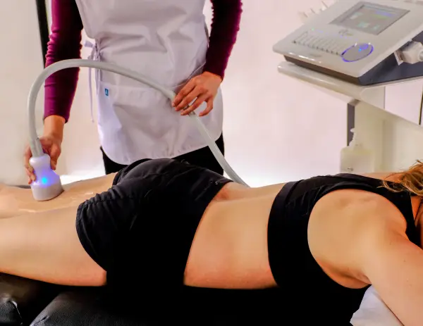 Woman relaxed while spa specialist applies Cryo T-shock device to client's back thigh for skin toning