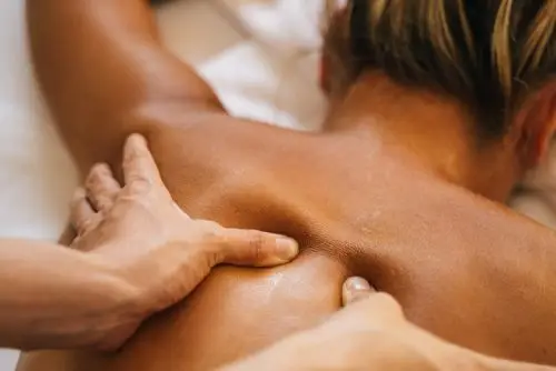 Massage therapy on a woman to release upper back tension.